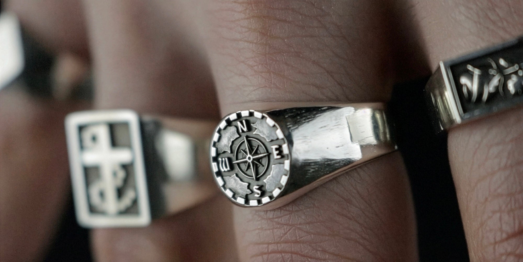 Three Jack Sterling sterling silver signet rings worn on a hand, with the Traveller compass signet ring in focus