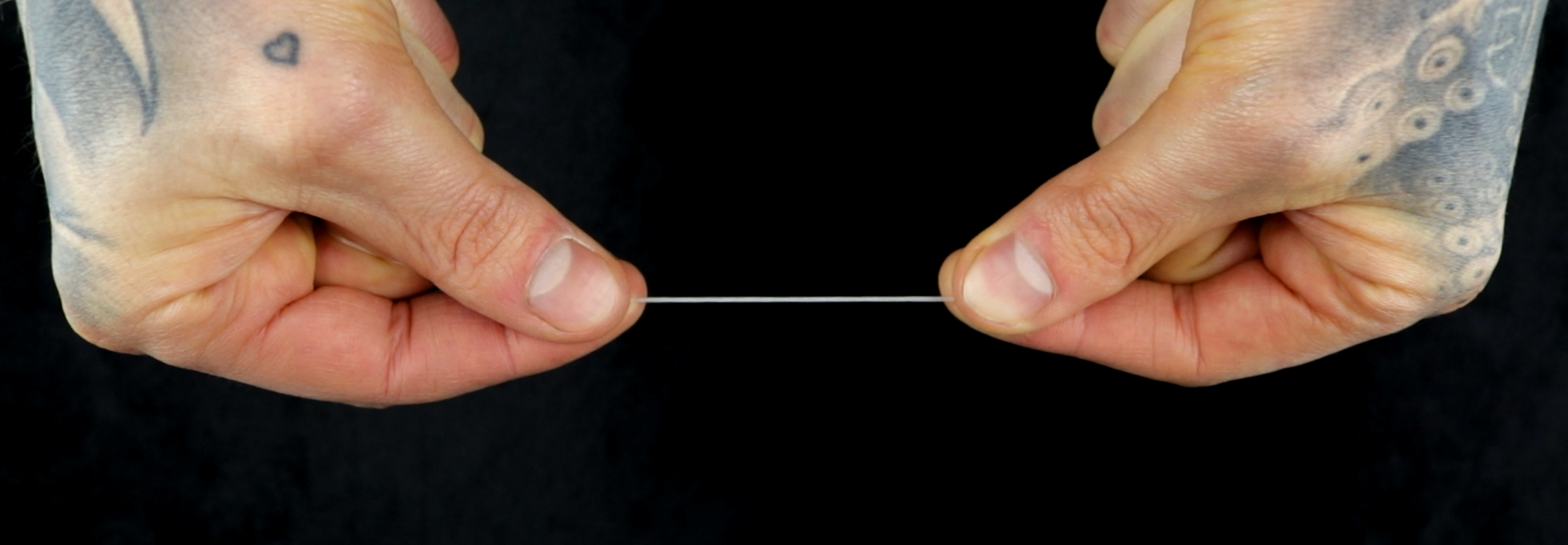 Hands holding a measured length of string between thumb and forefinger to check ring size, Jack Sterling sizing guide