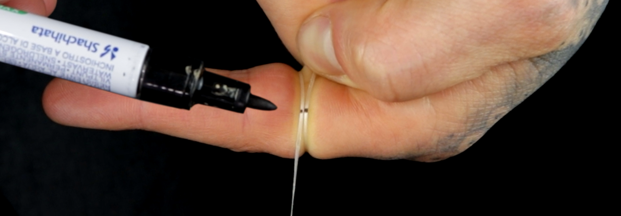 Marking a piece of string wrapped around a finger with a marker pen to measure ring size, Jack Sterling sizing guide